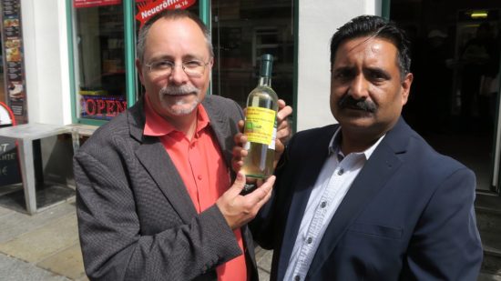 Spät-Shop-Chef Khalid Mazhar und Ortsamtsleiter André Barth mit beklebter Weinflasche.