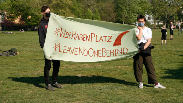 Mehrere Personen hatten sich in weitem Abstand mit Plakaten am Lautsprecherwagen versammelt.