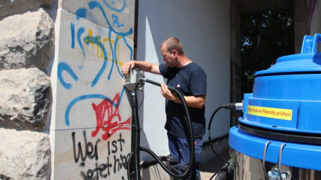 Marco Schulze entfernt einen Teil der Graffiti.