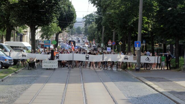Demo der Initiative "Stadt muss atmen" im Sommer 2021 - das Banner zeigt, wie die Straße ausgebaut werden soll.