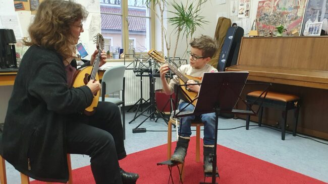 Birgit Pfarr bringt dem 8-jährigen Arthur das Mandolinen-Spiel bei.