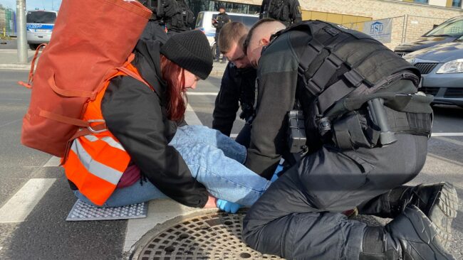 Mit Speiesöl löst die Polizei die angeklebte Hand einer Demonstrantin von der Straße ab. Foto: Letzte Generation