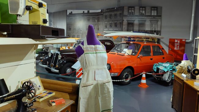 Automobile, Dederon-Schürze und Nähmaschinen. Bunt gewürfelte Ausstellung mit Produkten aus der DDR.