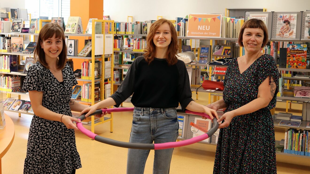 Die Bibo-Mitarbeiterinnen Laura Andrä, Helena Wnek und Dana Kuhnert präsentieren ausleihbare Dinge, hier den zusammensteckbaren Hoola-Hoop-Reifen.