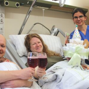 Die Leitende Hebamme Lisa Mühlberg gratuliert den frischgebackenen Eltern mit Brause und einer Windeltorte. Foto: Diako/Victor Franke