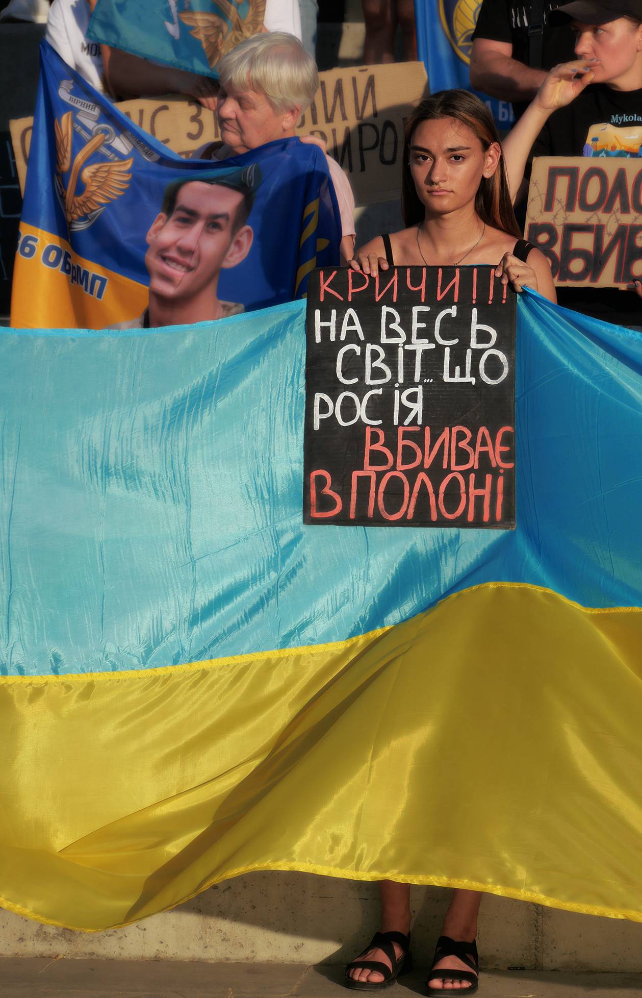 "Schrei laut in die Welt hinaus, dass Russland in Gefangenschaft tötet!" eine junge Ukrainerin mit Protestschild auf einer Demonstration in Mykolajiw (2022) - Foto: Sergiy Zholonko
