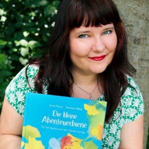 2026-02-25-enna-miau-mit-buch-vor-baum- Foto Ludwig Schmutzler