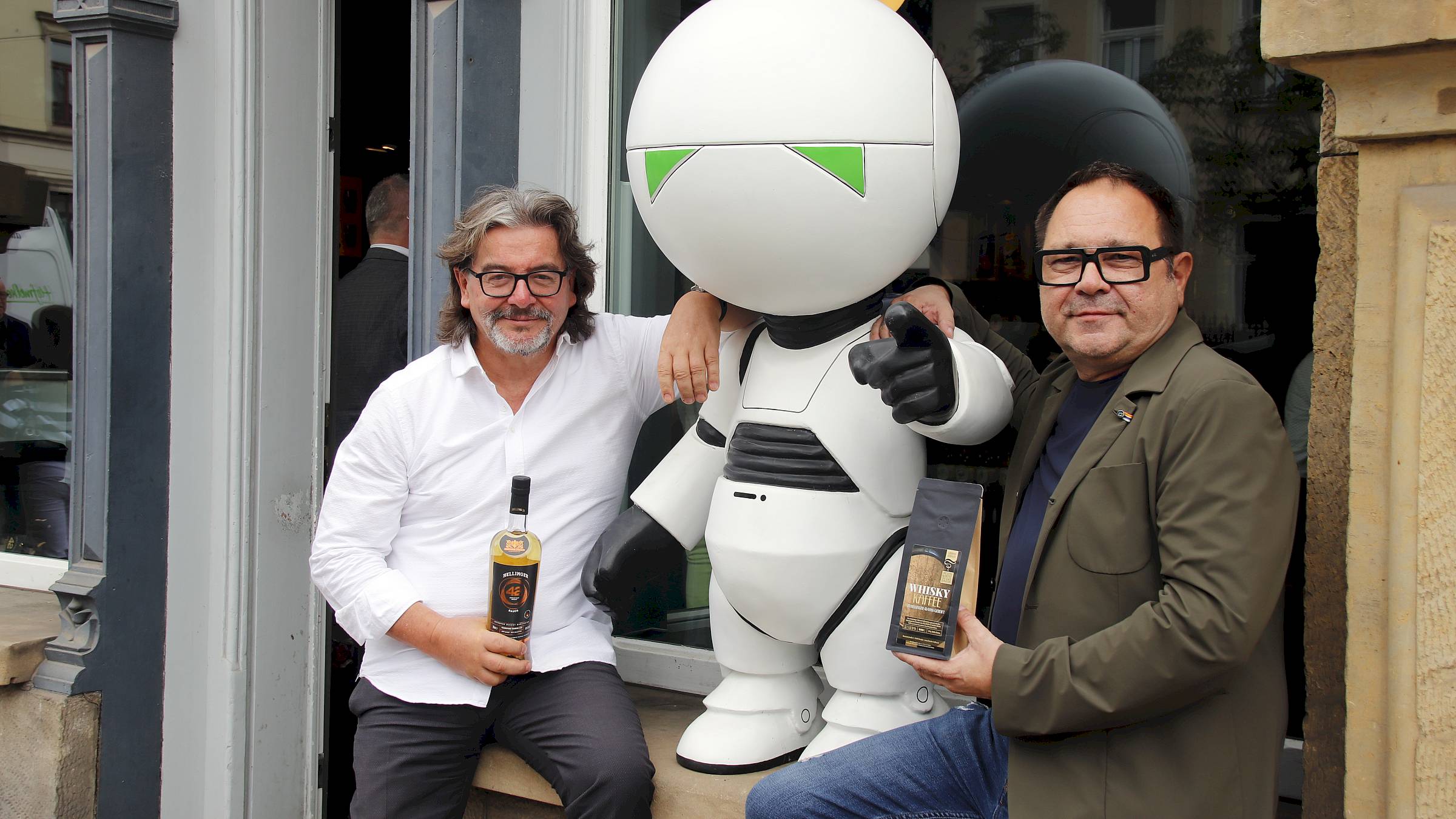 Frank Leichsenring und Karsten Lehmann mit Maskottchen Marvin. Leichsenring hat ganz offensichtlich ein Faible für Douglas Adams – daher auch die Nummer 42 im Namen des Whiskys. Marvin soll künftig Gäste in den Laden locken. Foto: Anton Launer